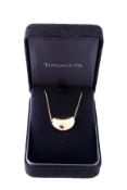 An 18 carat gold bean pendant by Elsa Peretti for Tiffany & Co., the polished bean on a fine