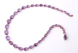 A late Victorian amethyst riviere necklace, circa 1900, the graduated oval shape amethysts each