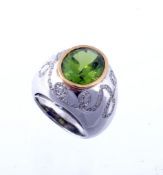 A peridot and diamond bombe ring, the collet set oval shaped peridot, on a wide band set with