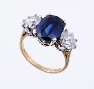 A sapphire and diamond three stone ring, the central oval shaped sapphire, weighing 5.62 carats, in