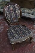 A Victorian carved walnut salon chair with an oval padded backrest and serpentine fronted seat on