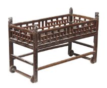 A Chinese stained hardwood crib, 19th century, cornered by carved beast finials, fretwork sides,