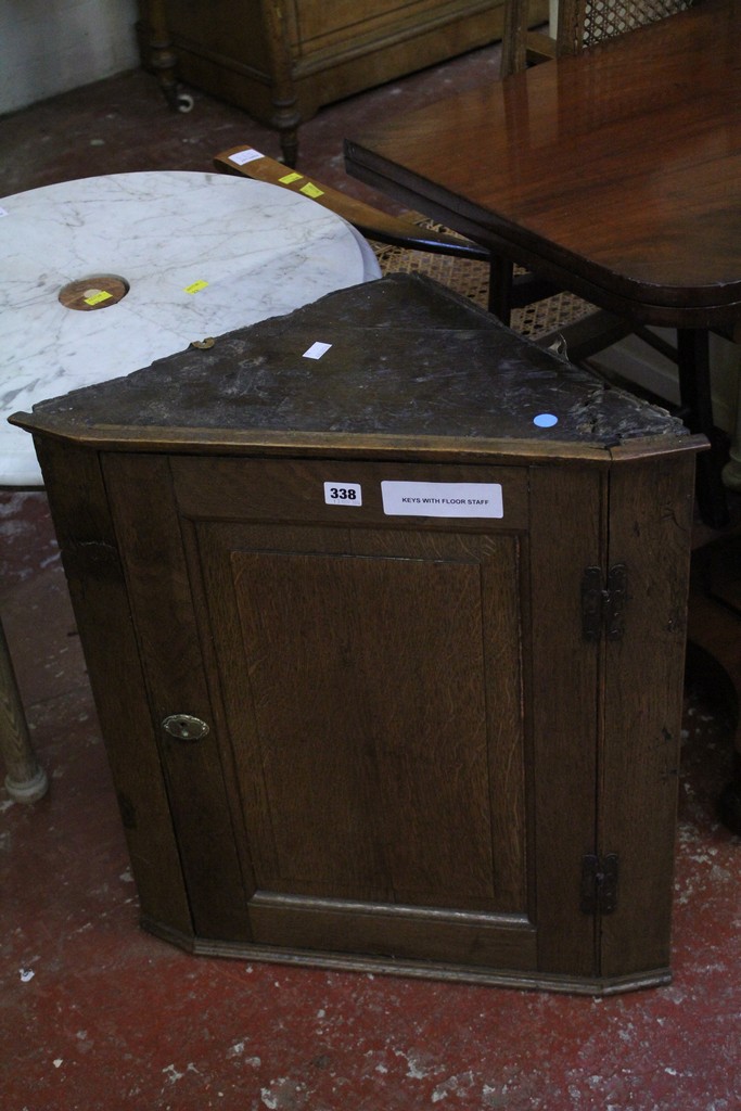 An oak hanging cabinet with a fielded panel door enclosing shaped shelves 57.5cm width.