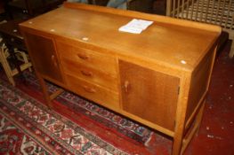 A 1940`s light oak sideboard with three short drawers flanked by cupboards bearing label P.E GANE