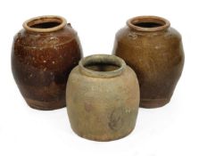 Three Chinese brown glazed pottery jars, of varying form, 42cm, 42cm, 32cm respectively