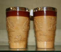 A pair of Doulton salt glaze beakers with silver rims. There is no condition report available for