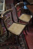 A set of four Regency brass inlaid dining chairs with cane seats and sabre legs