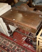 A Victorian oak side table with a mask to the frieze drawer on turned legs joined by stretchers