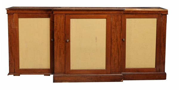 A mahogany breakfront cupboard, early 19th century and later, with fabric panel doors enclosing