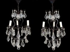 A pair of metal and cut glass hung three light chandeliers in Louis XV style, of recent