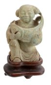 An unusual ceramic figure of a boy, he kneels holding a large carp in his arms, his head shaved to l
