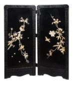 A Japanese two fold black lacquered screen decorated with inlaid designs of blooming flowers and