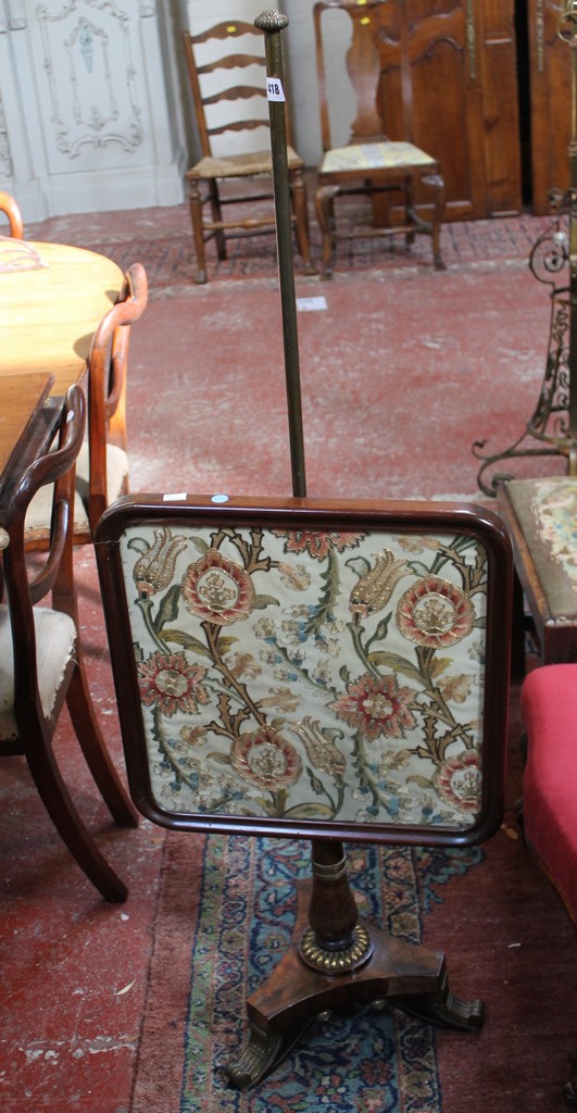 An early Victorian rosewood polescreen with framed needlework panel on triform base and on brass