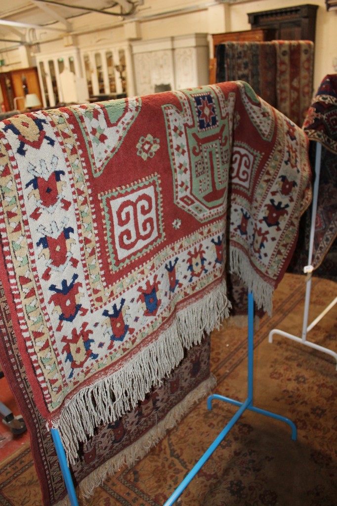 A Caucasian rug with central medallion stylised foliate border, green and coral ground, fringed