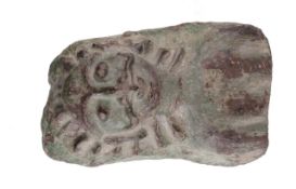 A carved stone head, depicting a human face with feline hair, bearing traces of green paint, 29cm