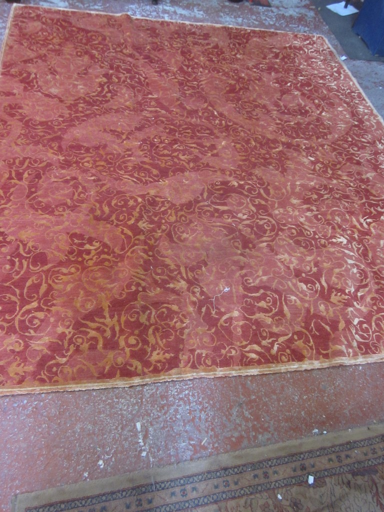 A red woven carpet, 20th century, with repeated scrolls throughout, in English taste 250 x 300cm