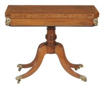 A Regency mahogany games table with hinged top, canted corners and quadripartite base with lion`s