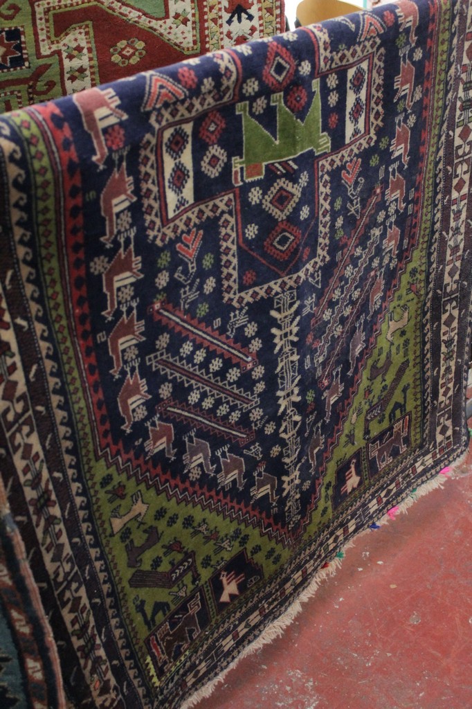 A blue ground rug with stylized decoration and animals 212 x 117cm. There is no condition report