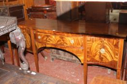 A George III mahogany inlaid sideboard of serpentine outline, central drawer flanked by drawer and