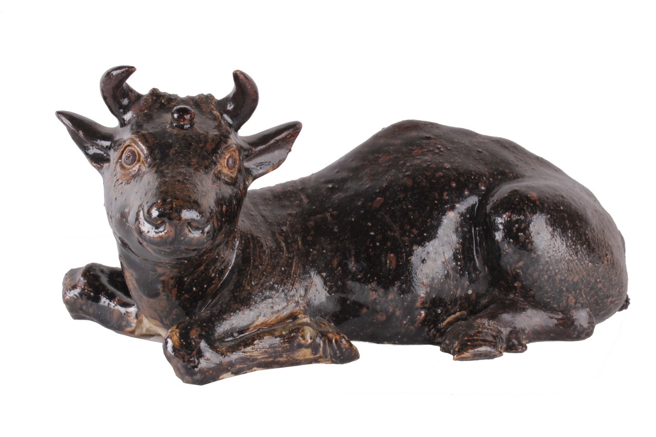 An Eastern pottery model of a reclining cow, with a brown glaze, 31cm. There is no condition
