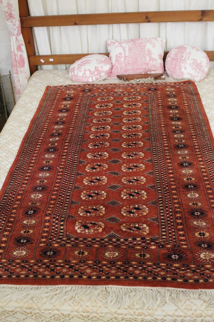 A modern Bokhara rug with twenty six guls, similar border, on coral ground, 152 x 96cm