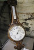 A late Victorian carved oak aneroid wheel barometer, the 10 inch circular white ceramic dial