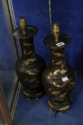 A pair of Chinese gold and brown lacquer bottle vases, decorated with dragons on scroll bases (