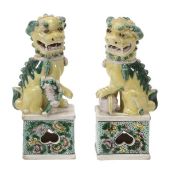 A pair of famille verte models of Buddhist dogs, 19th century, each in typical pose upon a