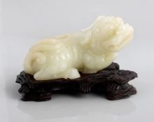 A jade model of a qilin, 19th century, the reclining creature with its legs tucked beneath it, its