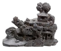 A black wood carving of a miniature landscape, elaborately rendered as a rustic summer retreat atop