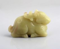 A yellow-green jade figure of a deer, 19th century, the reclining animal with all four legs tucked