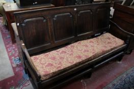 An early 19th century oak bench with panelled back and squab cushion on a strung seat . 183 cm