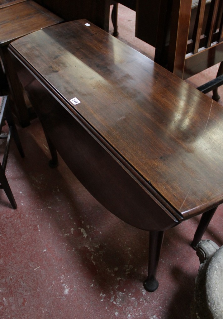 A Georgian oval drop leaf supper table with turned tapering legs and pad feet and an early 19th