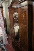 An Edwardian inlaid bedroom suite comprising wardrobe with mirror door, dressing chest on four legs