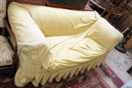 An Edwardian Chesterfield style drop-end sofa with loose yellow covers.