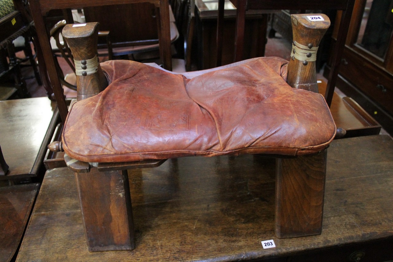 A camel stool with leather pad seat
