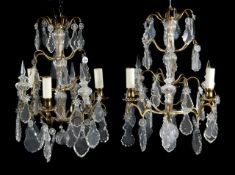 A pair of gilt metal and glass hung three light chandeliers, 20th century, the electrical fitments