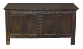 An oak panelled coffer, 17th century, with hinged top, above a guilloche carved frieze on stile