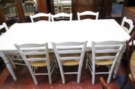 A kitchen table and eight rush seat kitchen chairs all in a white painted finish