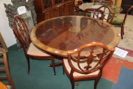 A circular mahogany dining table with satin and rosewood banding on a central with swept supports