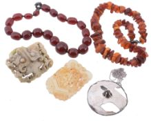 An amber bead necklace, of rough form; a red bead necklace; a pendant; and...  An amber bead
