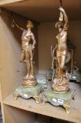 A pair of gilt metal statuettes modelled as classical male and female figures held on oynx bases;