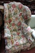 A Georgian style wing back armchair in loose floral covers.