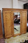 A Victorian triple front and mirror door satinwood wardrobe enclosing linen slides drawers and