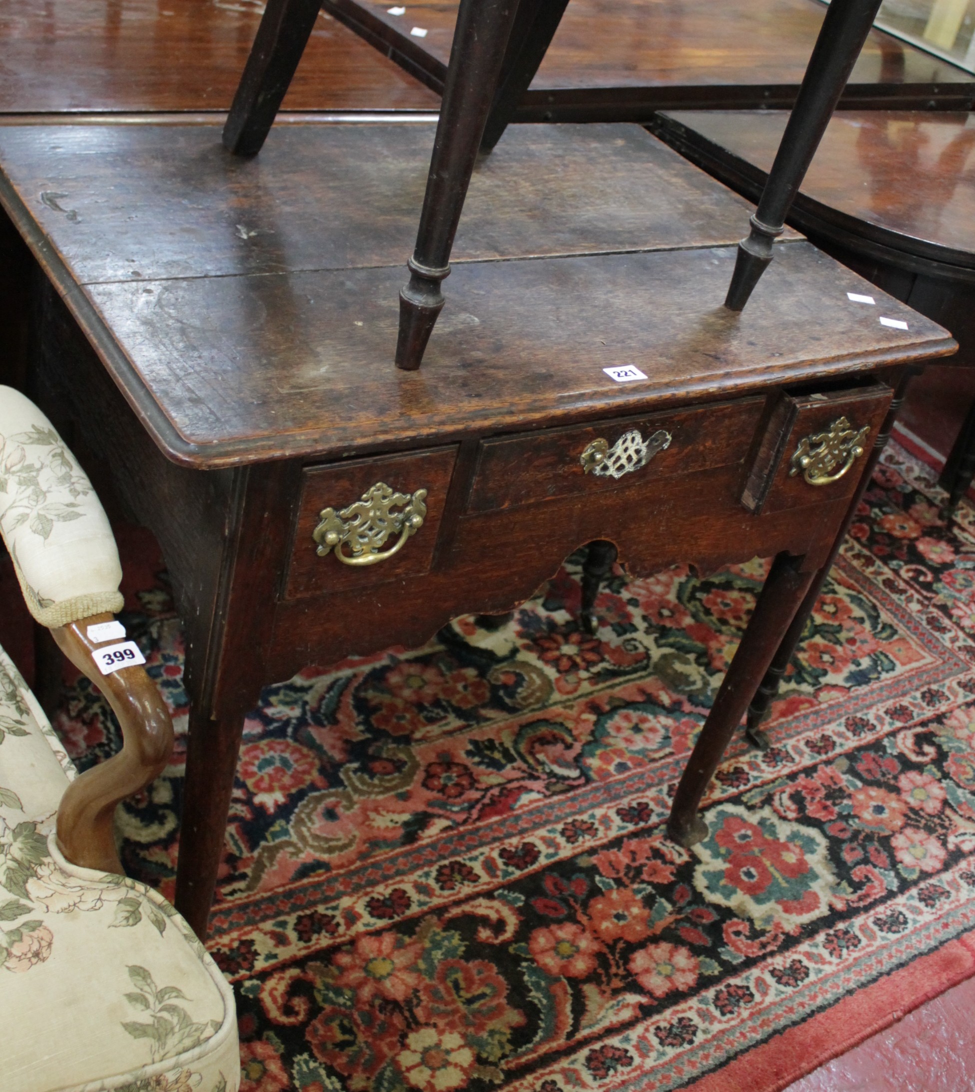 A George II oak side table with three frieze drawers with a shaped apron on turned tapering legs