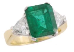 An emerald and diamond three stone diamond ring, the step cut emerald with canted corners,