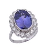 A tanzanite and diamond ring, the central oval cut tanzanite in a collet setting, within a