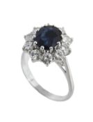 A sapphire and diamond ring, the central oval cut sapphire, claw set within a surround of