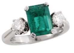 An 18 carat gold emerald and diamond three stone ring, the central rectangular step cut emerald in a