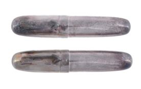 A silver coloured torpedo shaped fountain pen and ball point pen, both with a polished barrel and